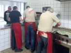 Markus und Damir arbeiten am Kartoffelpüree, Detlef schneidet das Fleisch